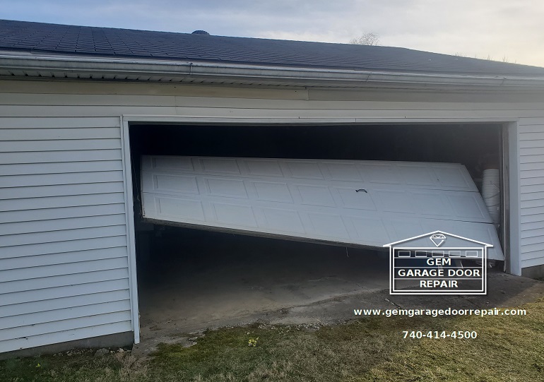 Before photo showing crumpled garage door panel